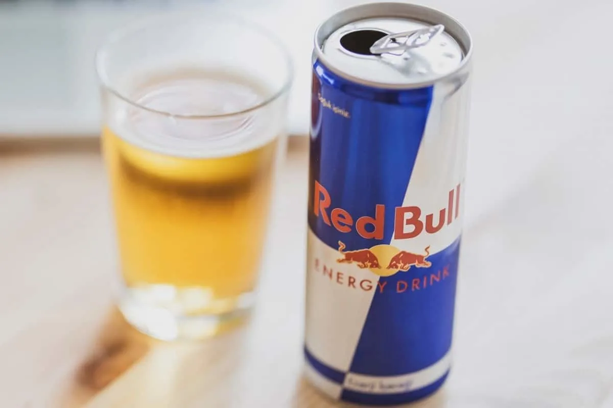 A can of Red Bull with a glass beside it.