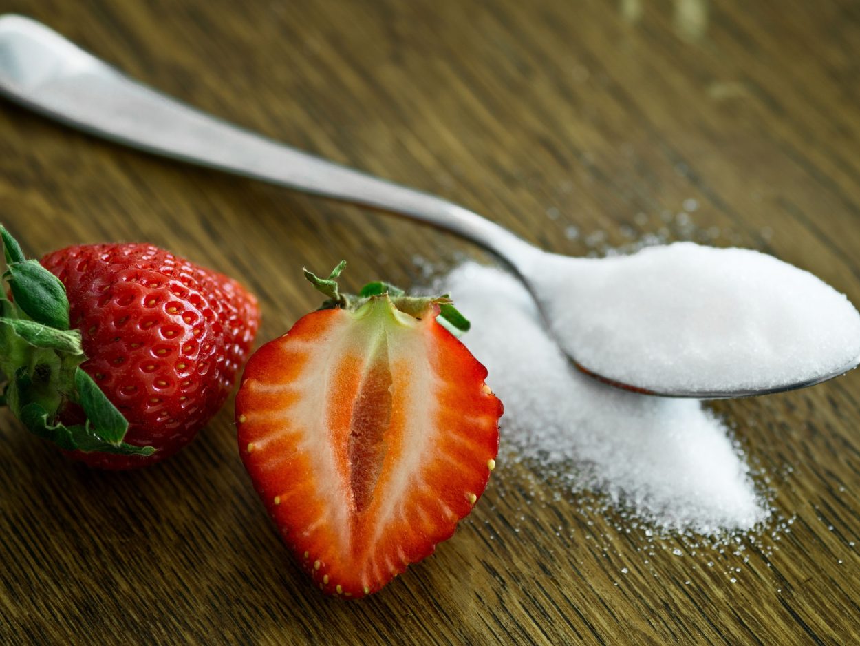 A strawberry next to sugar