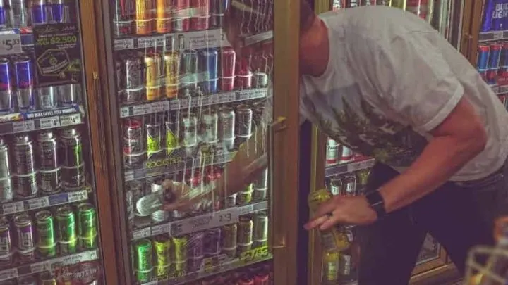 a man taking an energy drink from fridge in a store