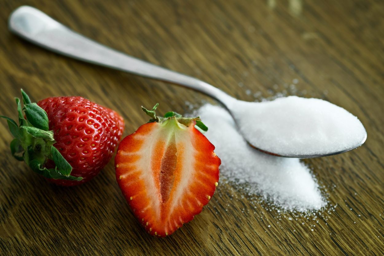 A sugar containing spoon on a surface