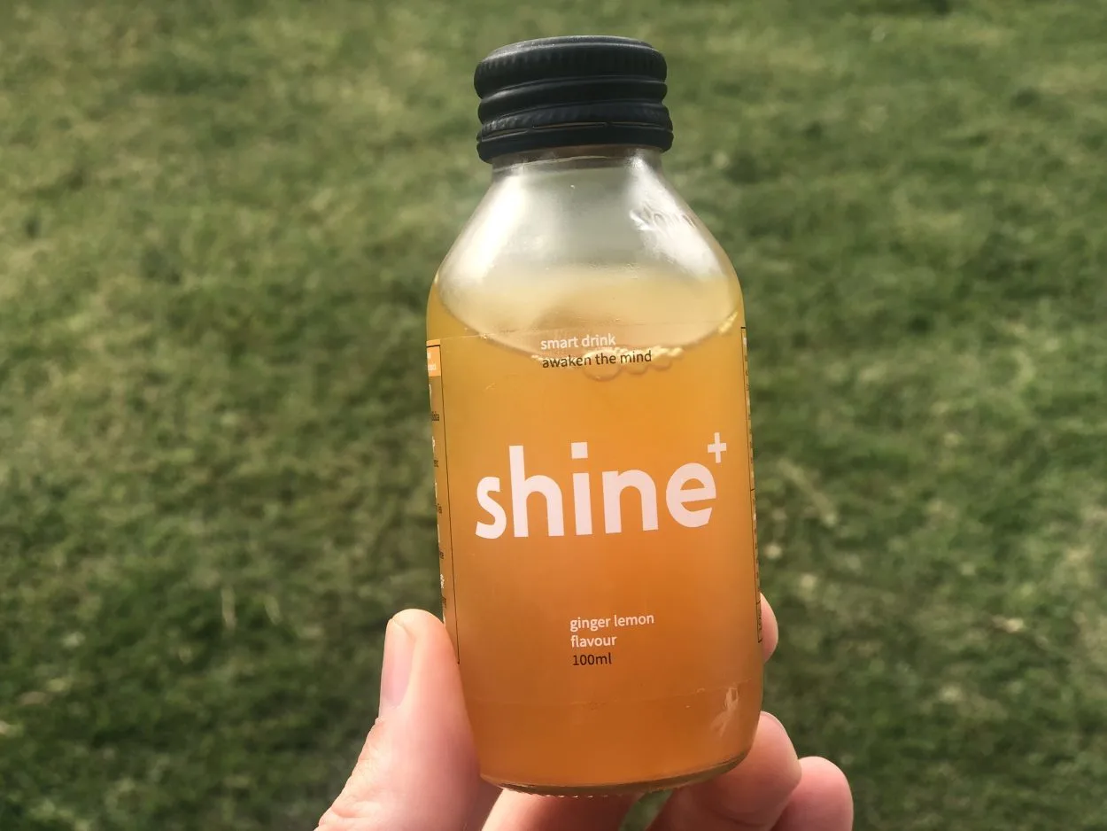 A person holding a shot of Shine energy drink