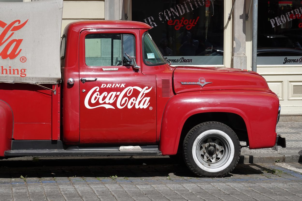 Midium sized truck painted red and has the Coca-Cola logo 
