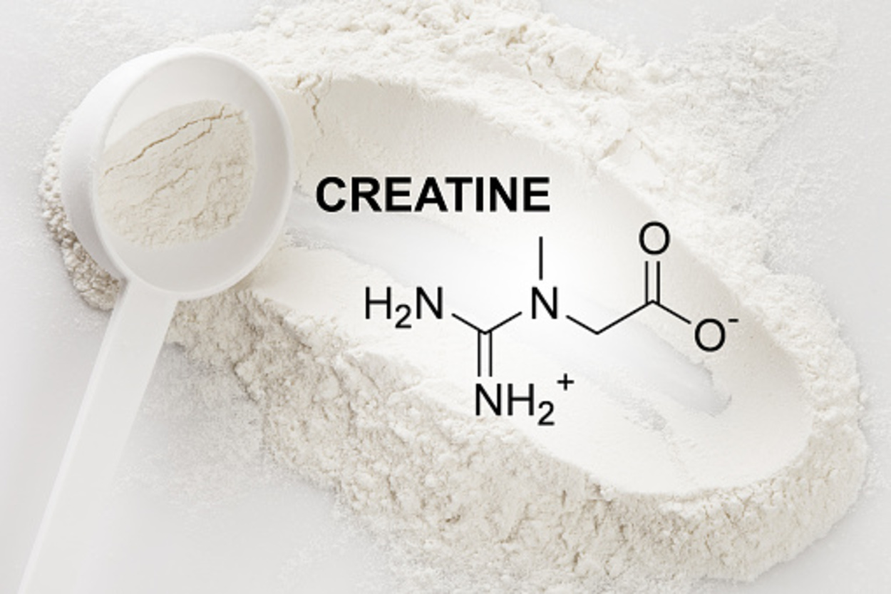 Closeup of a scoop with creatine monohydrate supplement and chemical formula