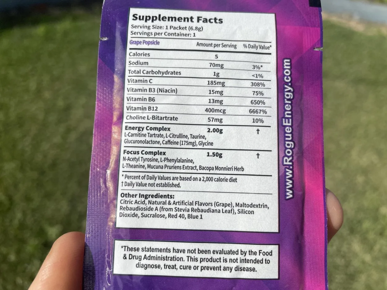 A person holding a sachets of Rogue Energy facing its nutritional facts label