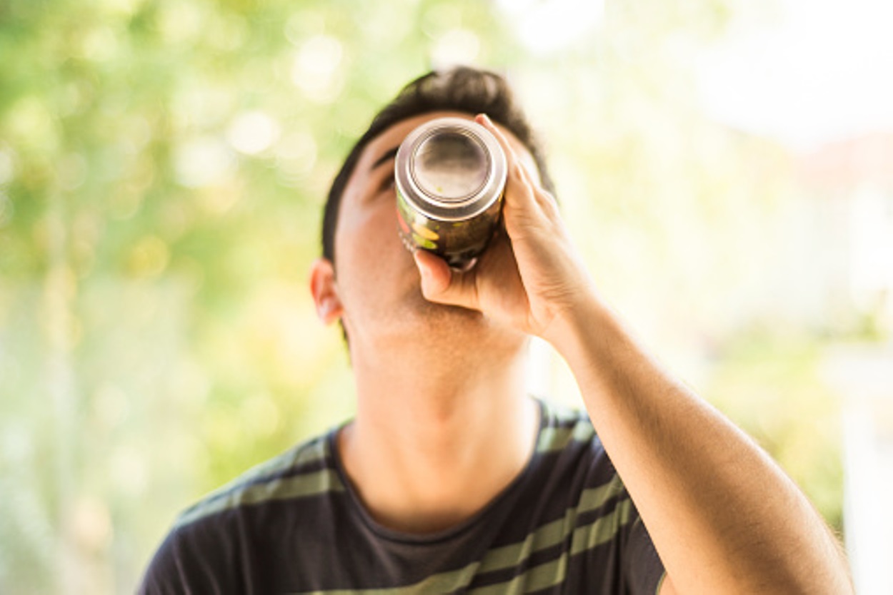 A young man drinking an energy drink can.