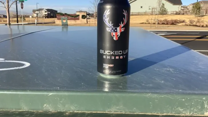 A can of Bucked Up on Green colored surface
