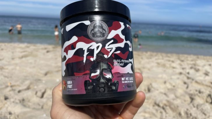A person holding a tub of Outbreak Nutrition energy powder on the beach