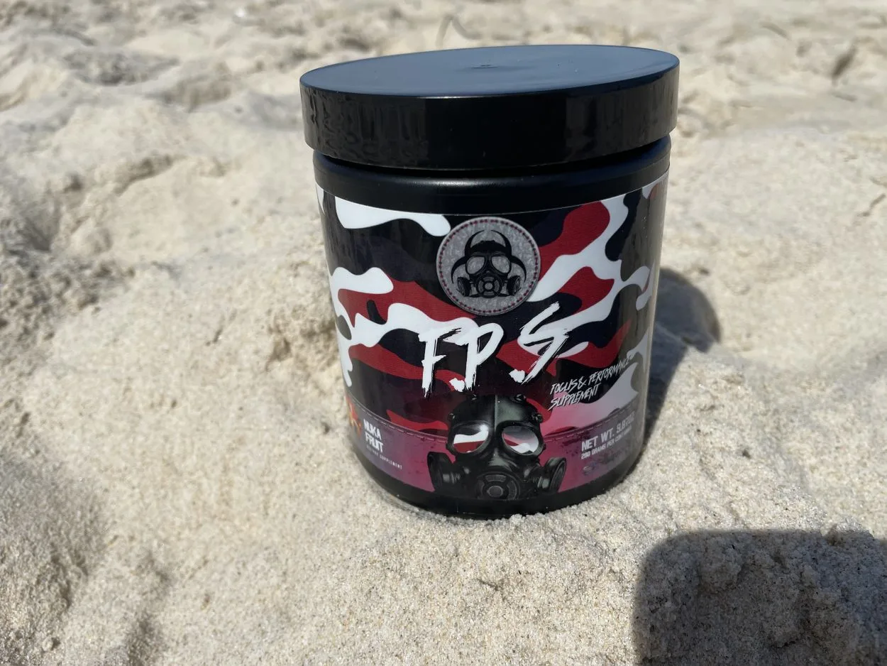 A tub of Outbreak Nutrition Energy Powder placed on sand