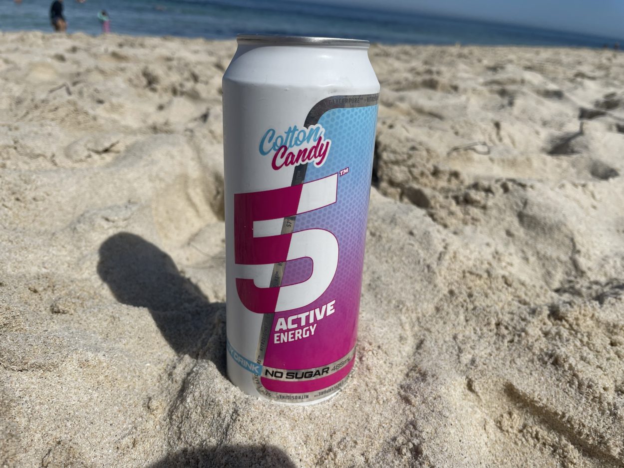 A can of 5 Active Cotton Candy energy drink placed on sand