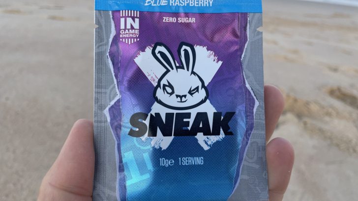 A person holding a sachet of Sneak energy in blue raspberry flavor
