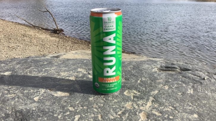 A can of RUNA Clean with a lake behind it
