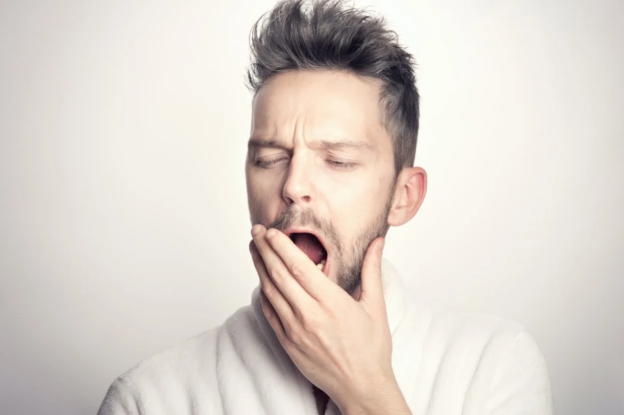 A man in white t-shirt yawning
