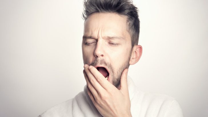 A person in white t-shirt yawning
