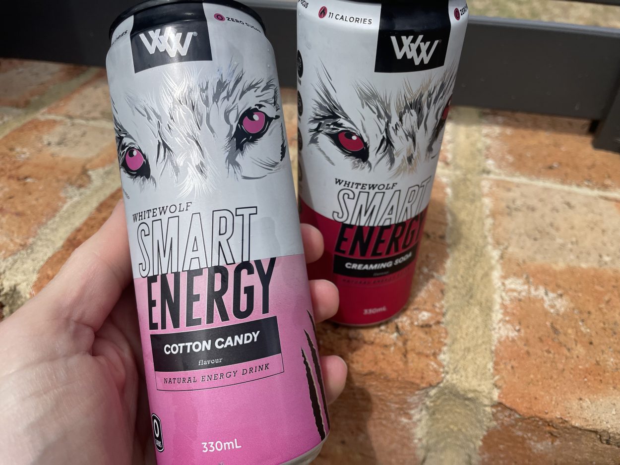 A person holding a can of White Wolf Smart and one can placed beside 