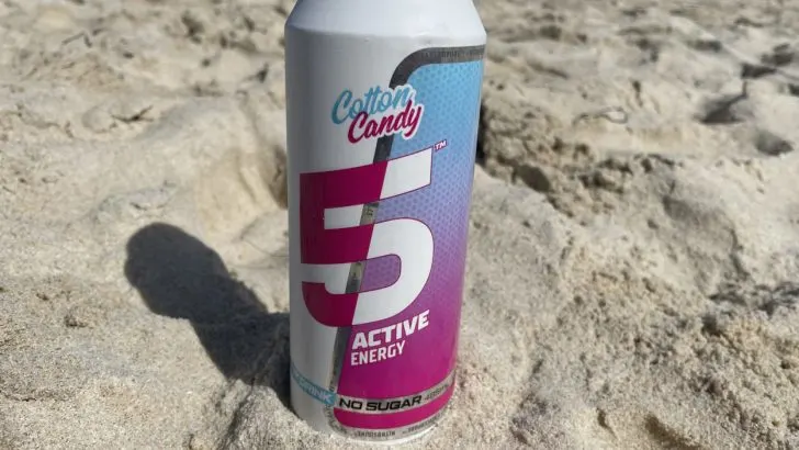 A can of 5 Active energy drink placed on the sand on a beach