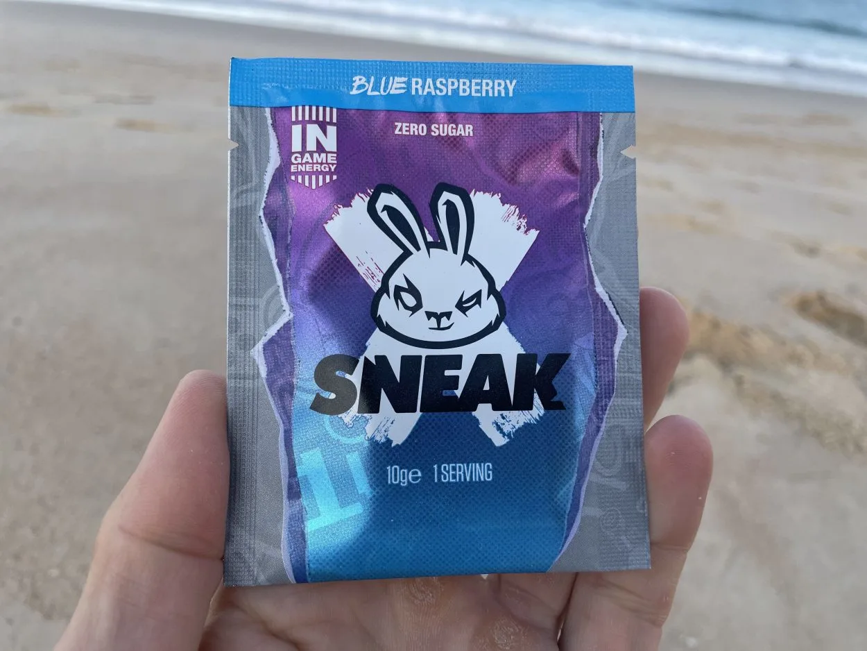 A person holding a sachet of Sneak energy in Blue Raspberry flavor