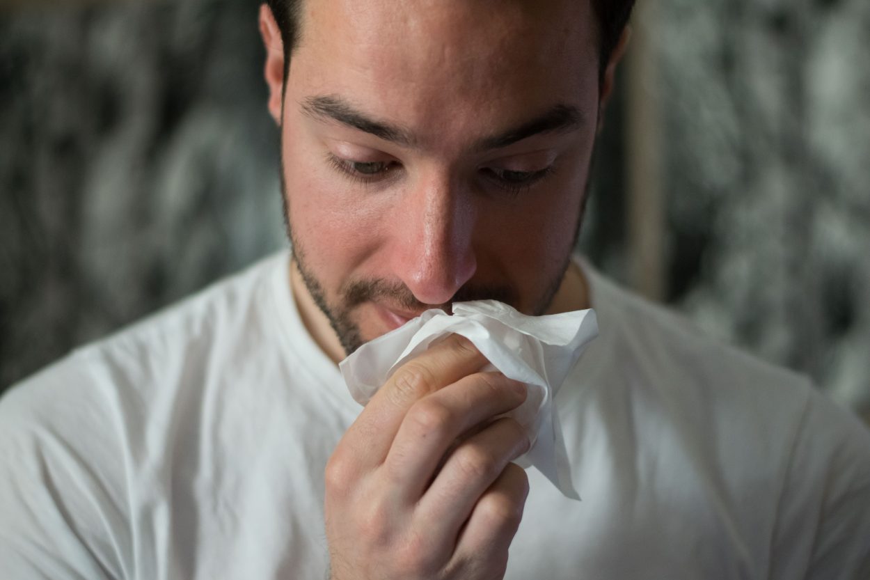 A man in white t shirt wiping his mouth with tissue