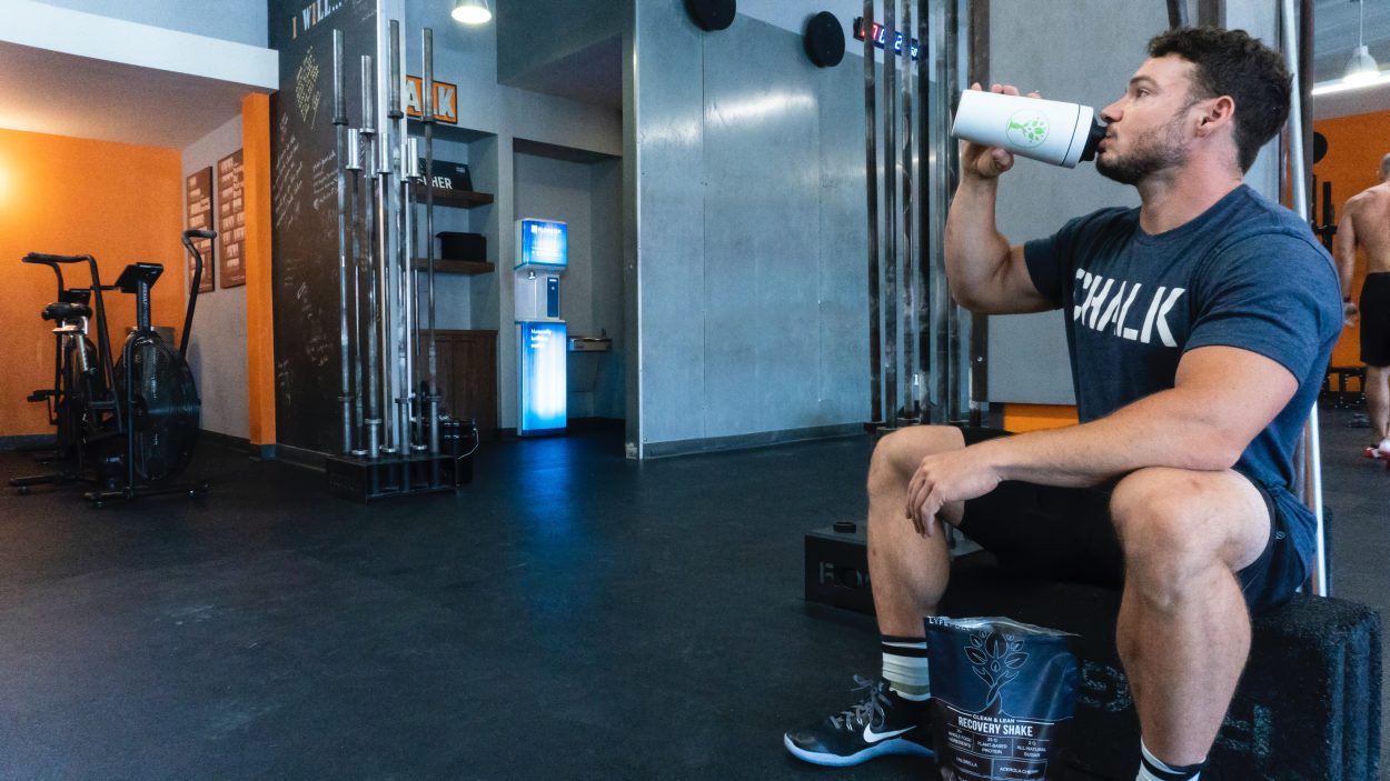 A man drinking protein from the shaker in a gym